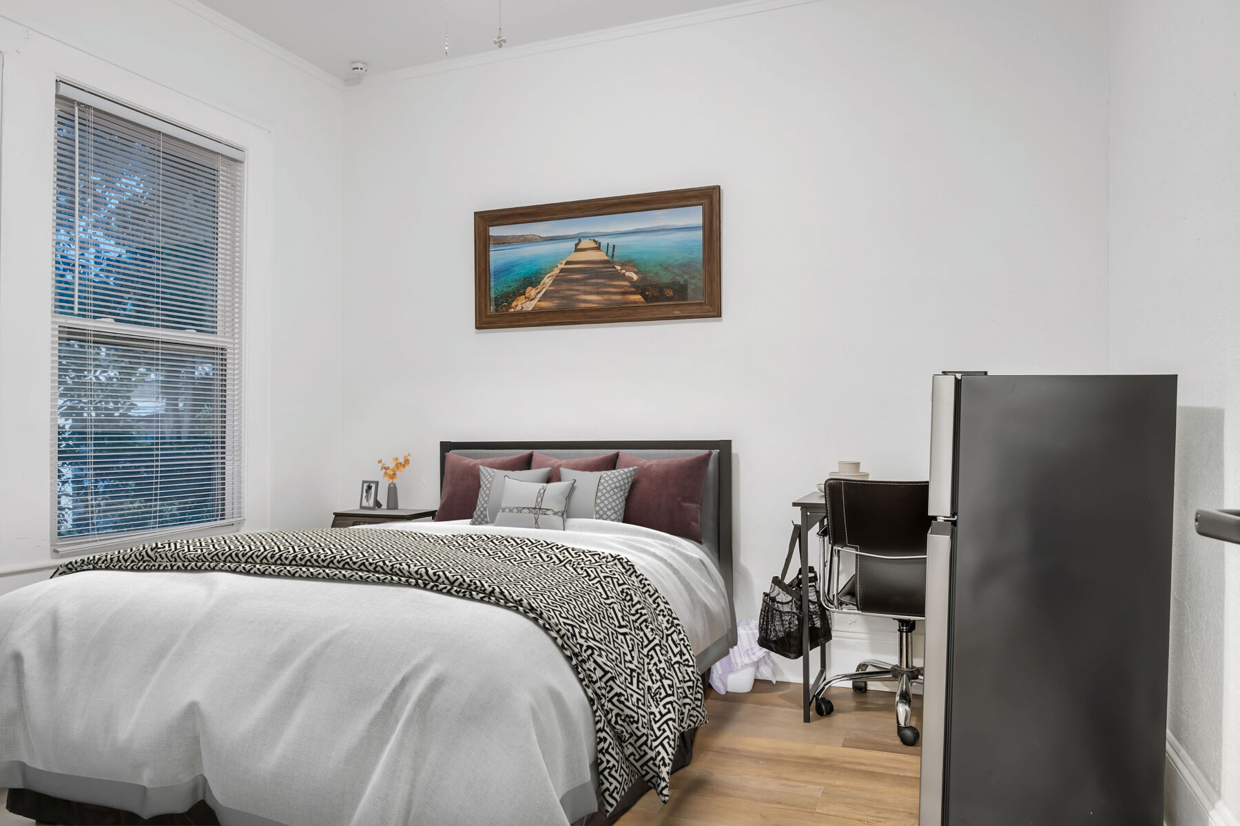 A modern bedroom with a mural hanging over a bed.