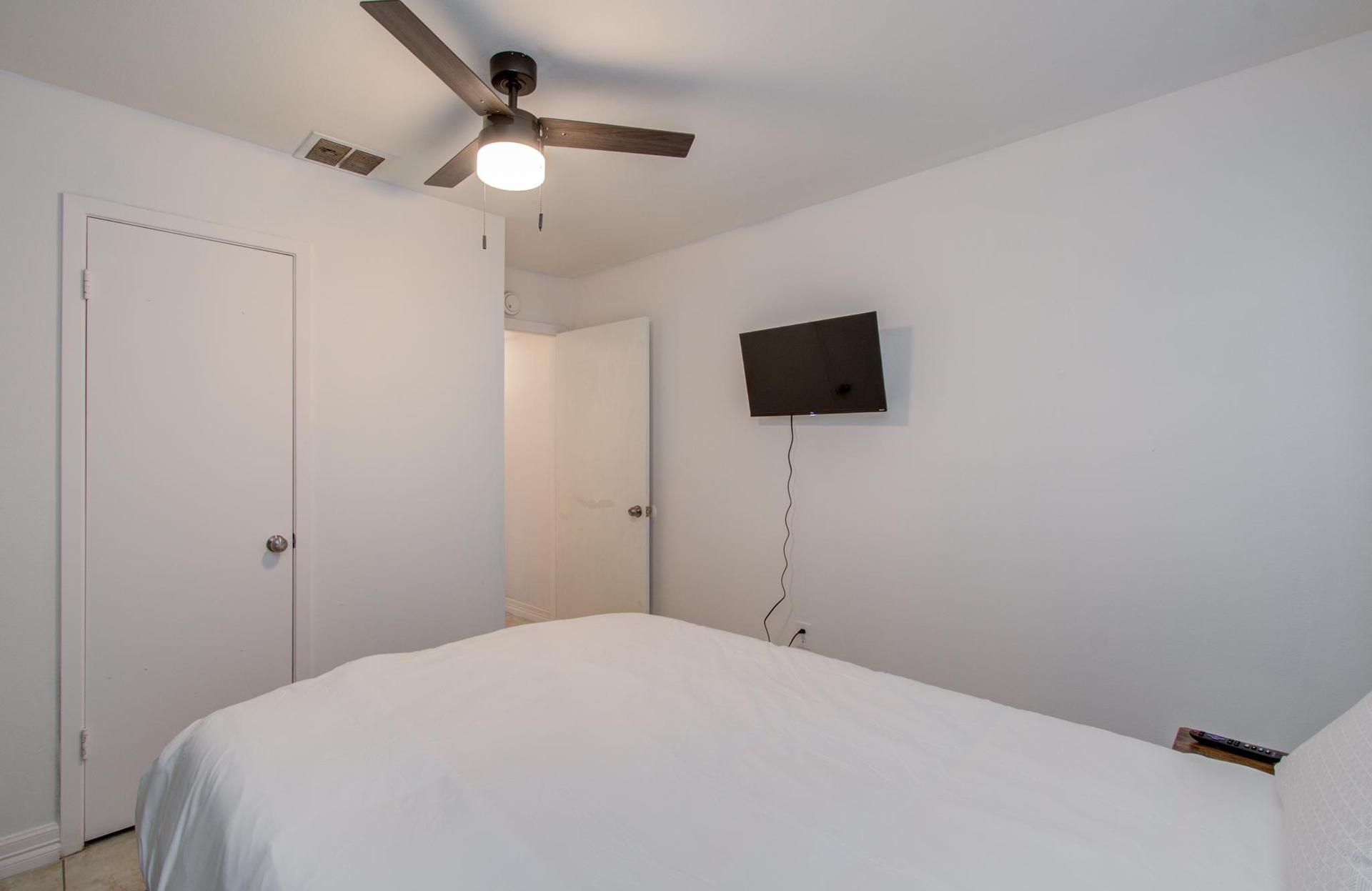 Bedroom next to bathroom with smart TV and closet. Window faces the street.