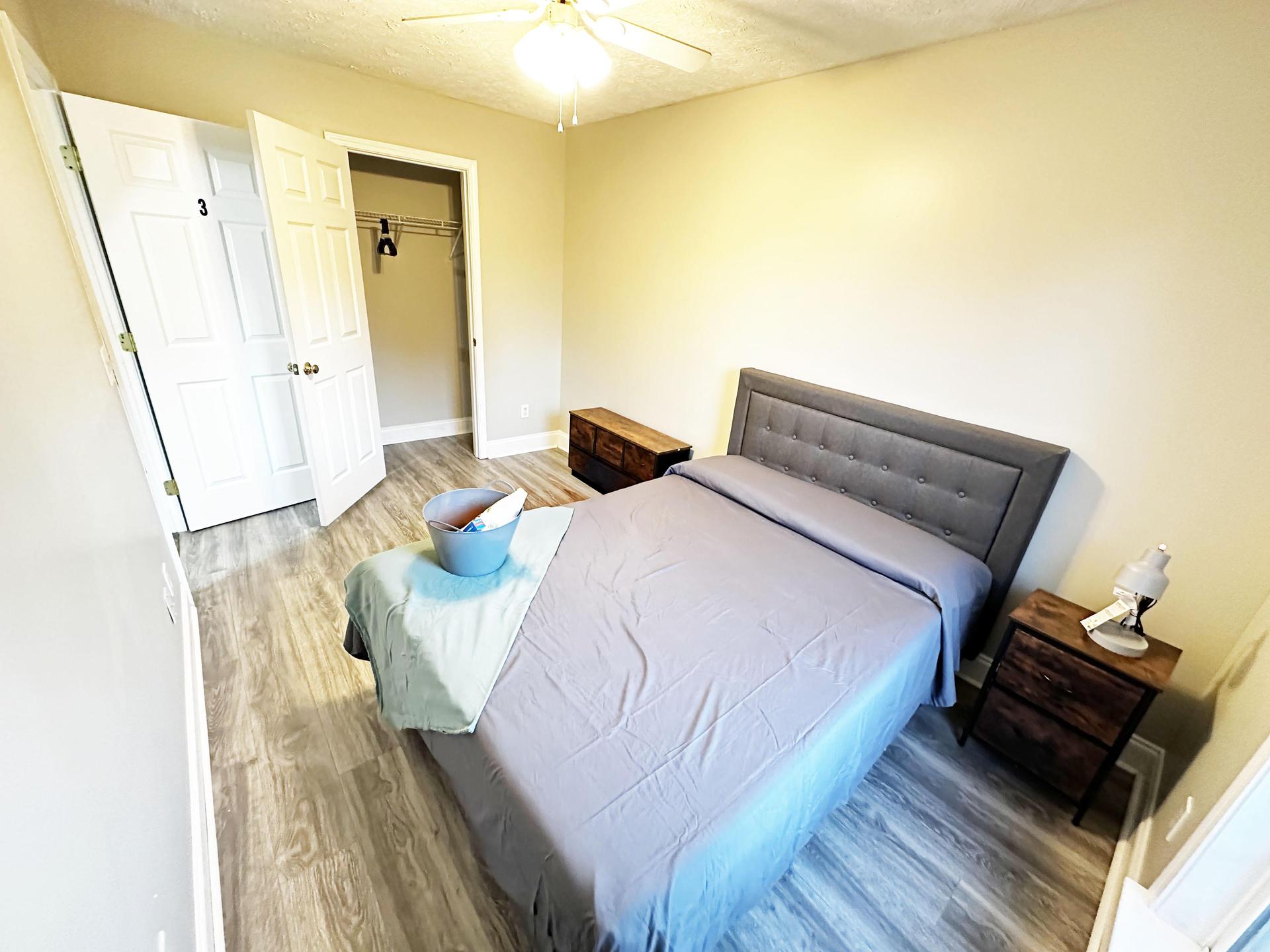 Large bedroom with large window and dress and a closet