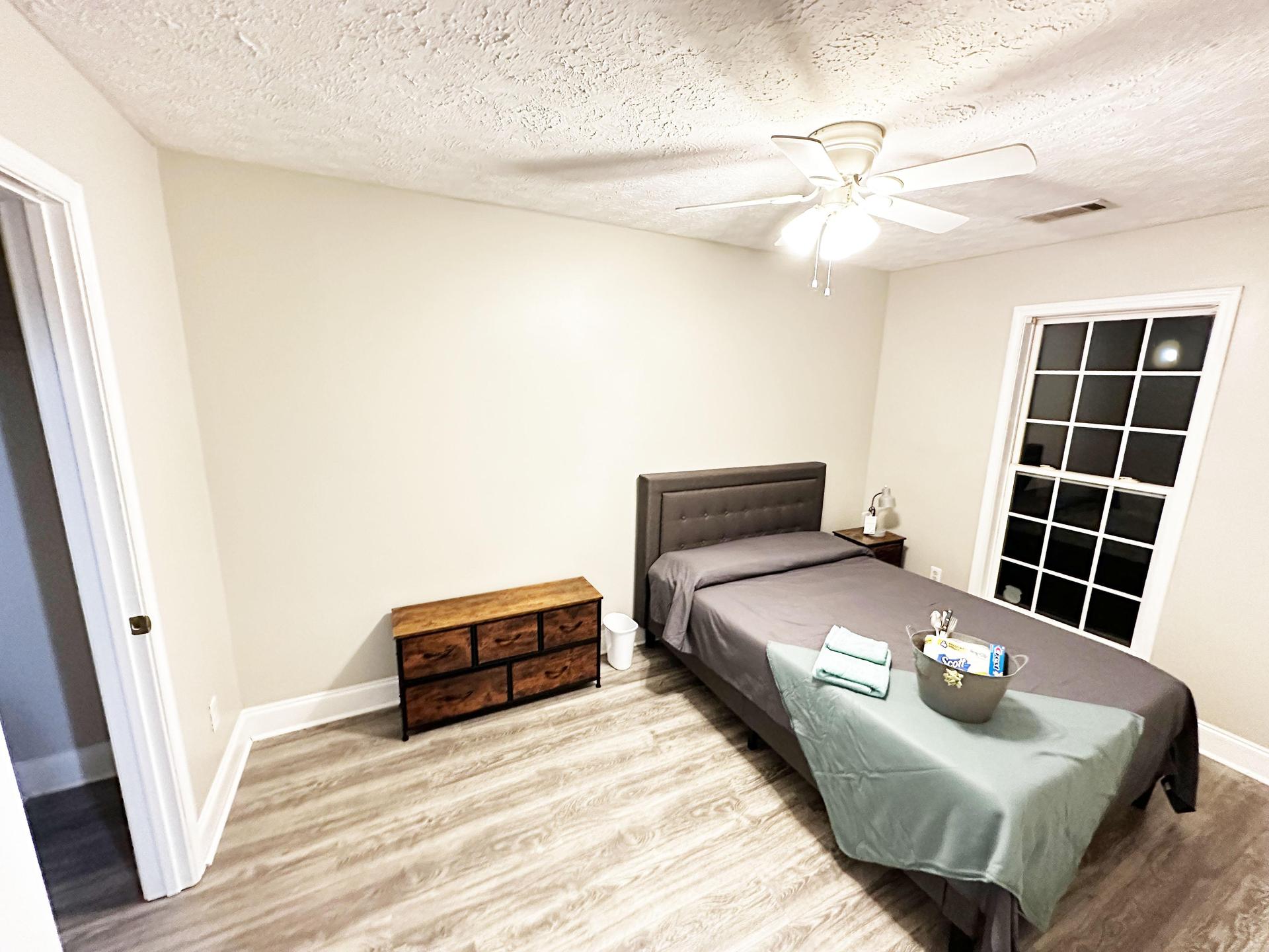 Large bedroom with large window and dress and a closet