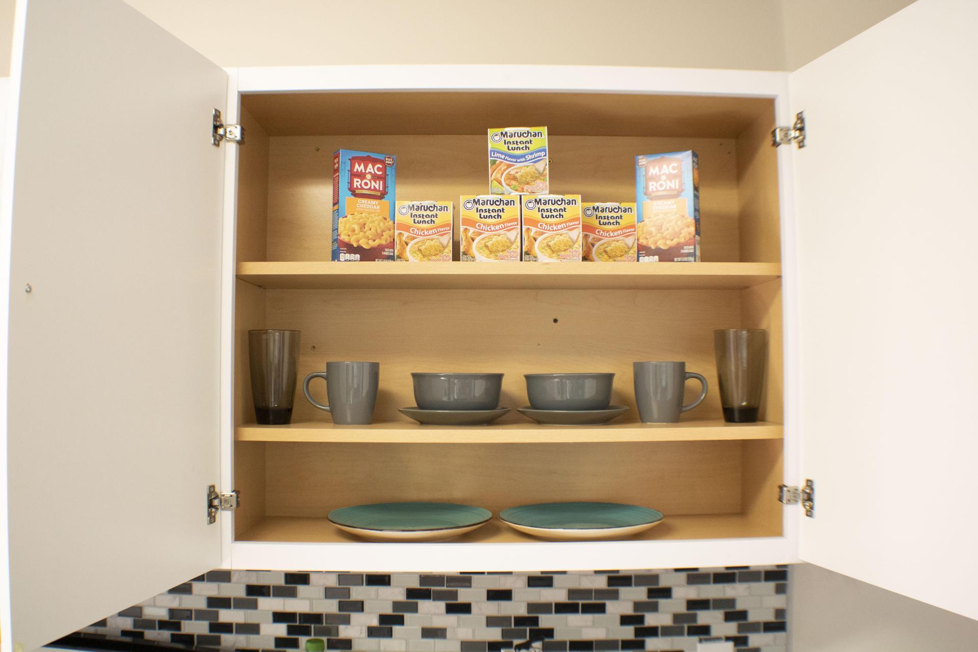 Labeled Kitchen cabinet with Personal plates and bowls for 2, with some food for good  measure