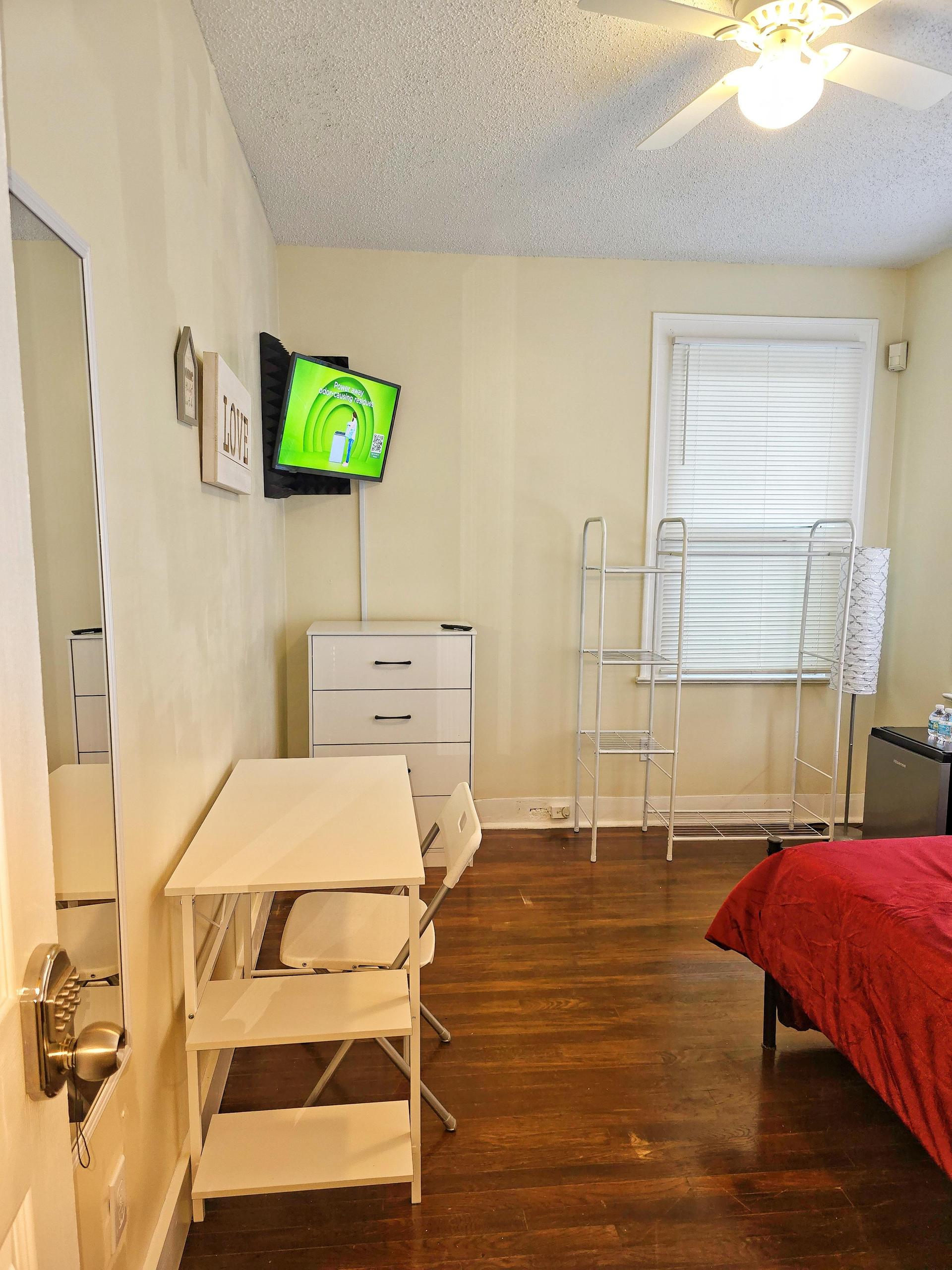 Room 2 is a corner room equipped with a full bed, linens, TV, mini fridge, desk, chair, nightstand, clothing rack,  dresser!