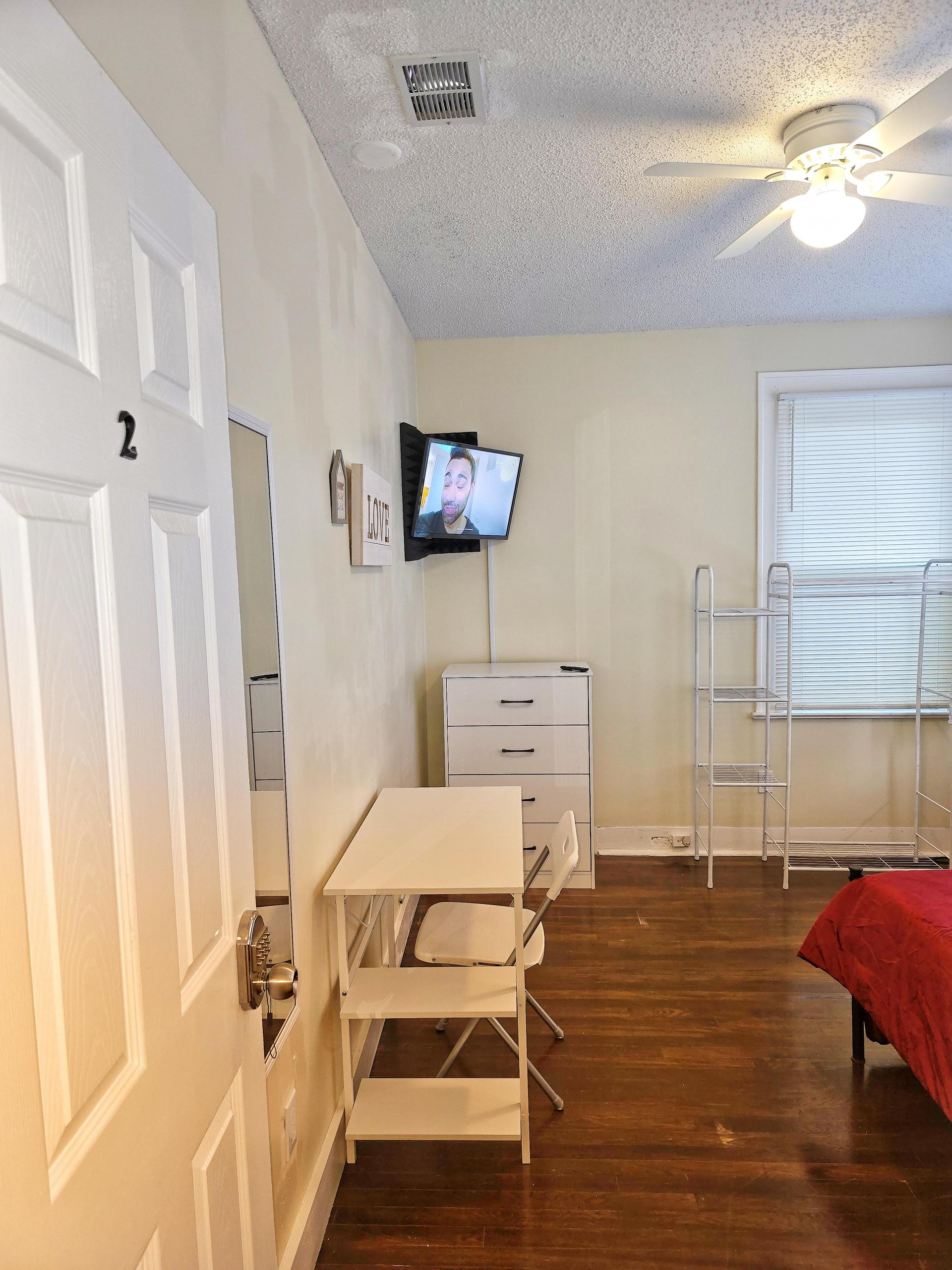 Room 2 is a corner room equipped with a full bed, linens, TV, mini fridge, desk, chair, nightstand, clothing rack,  dresser!