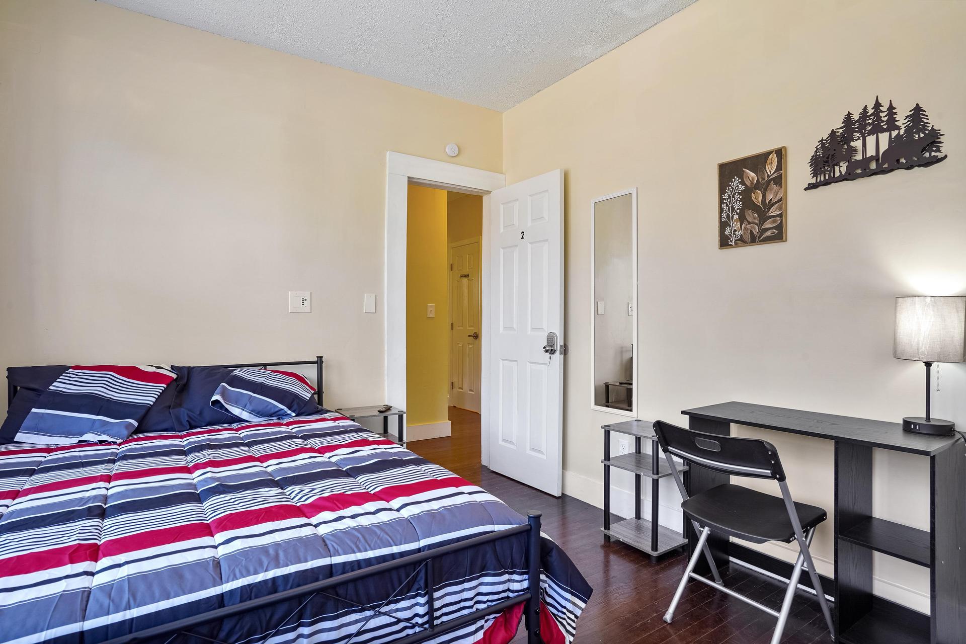 Room 2 is a corner room equipped with a full bed, linens, TV, mini fridge, desk, chair, nightstand, clothing rack,  dresser!