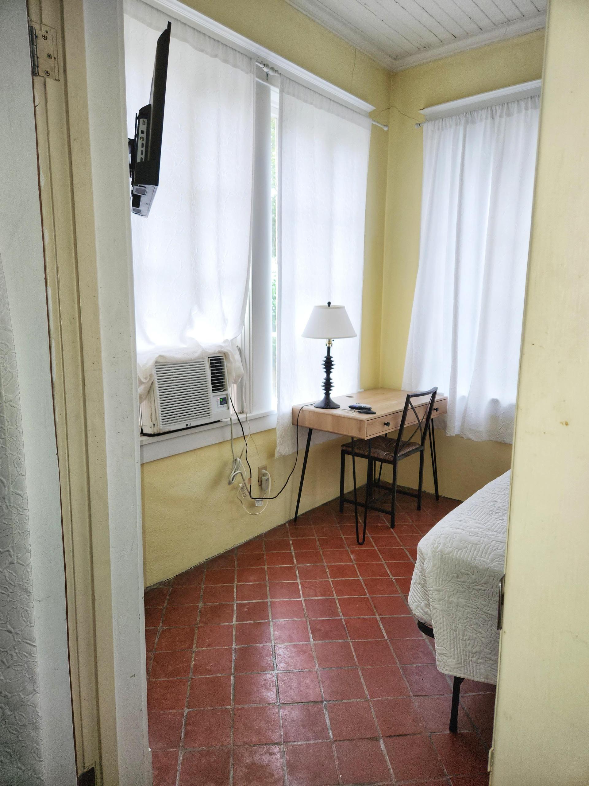 Noire room. A bright courtyard view with 5 windows, Queen bed, tile floor, window AC/Heat unit, dedicated work station and TV