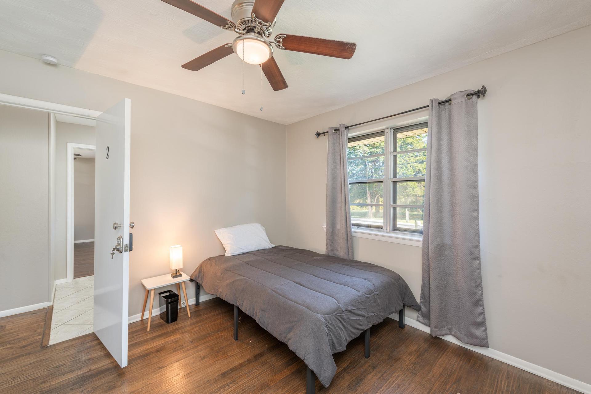 Room equipped with a full sized bed, dresser, closet, trash can, night stand and night light. Front of the house bedroom.