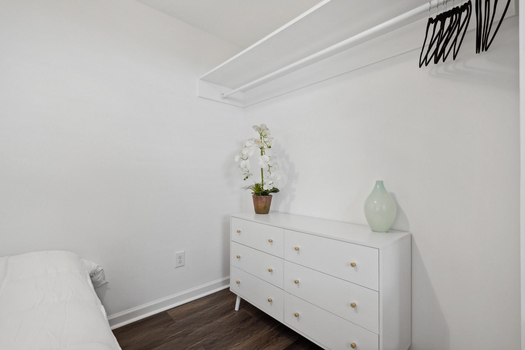 Close Up View of the Clothes Hanging and Dresser Area