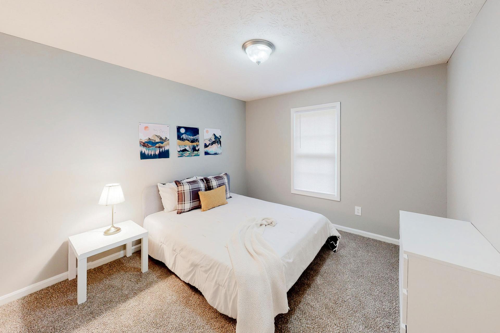 Spacious bedroom featuring a queen bed, nightstand, dresser and reach-in closet.