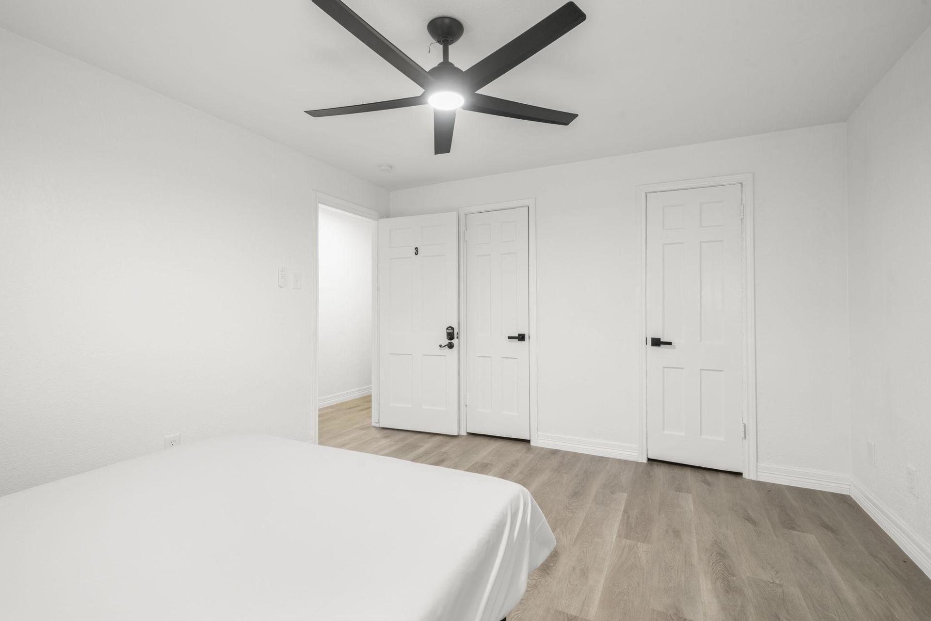 Standard room w/ queen bed, writing table, ceiling fan.