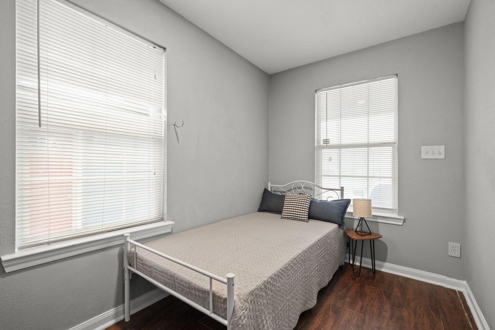 Twin sized bed & mattress in a cozy bedroom w/ writing desk & chair,  closet rack.