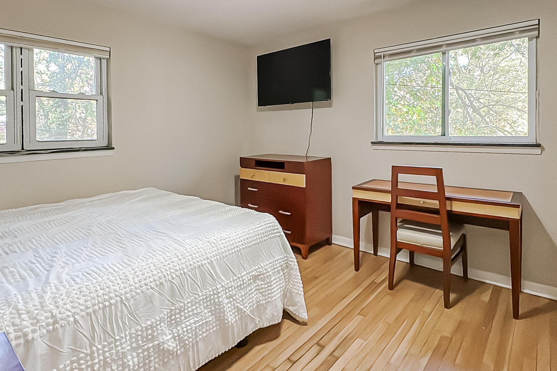 This room has two windows, a desk with chair, plus a lounge chair, but there is no closet- only a dresser.