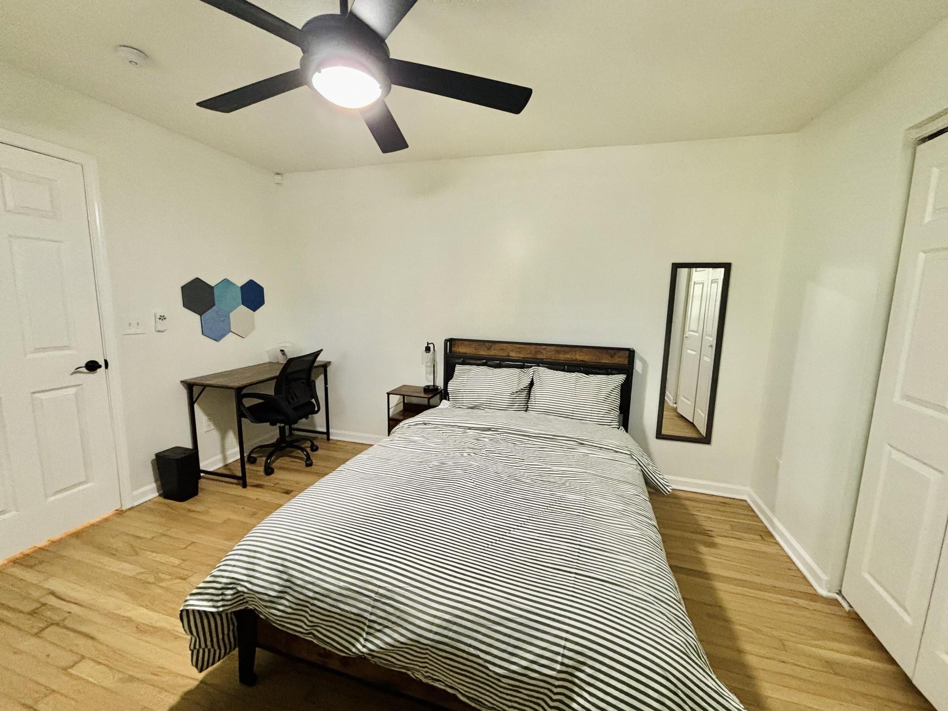 Spacious bedroom with full sized bed, mounted smart TV, desk & bulletin board, and full length mirror!