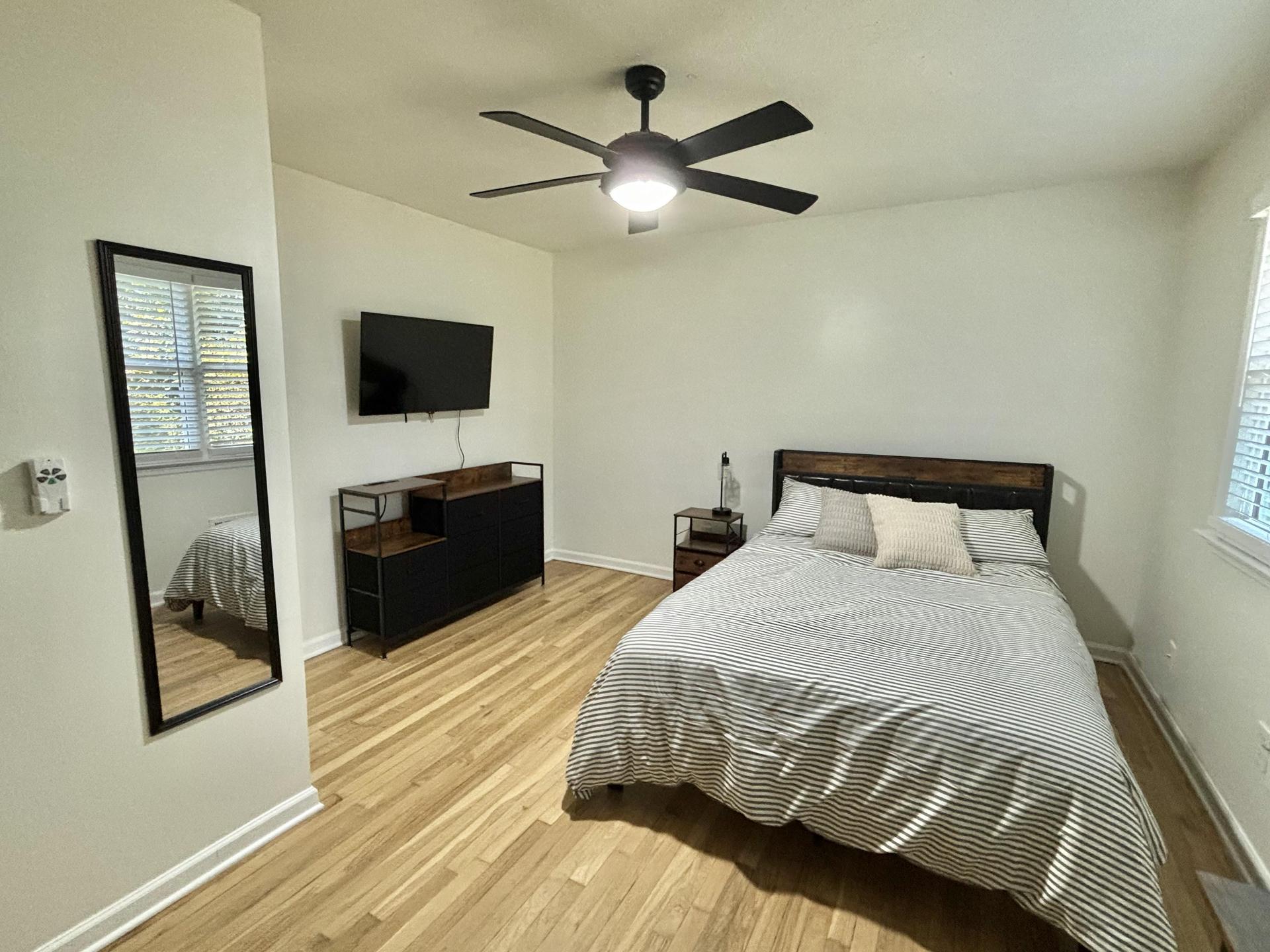 Spacious bedroom with full sized bed, all linens included, mounted smart TV, desk, bulletin board, and full length mirror!