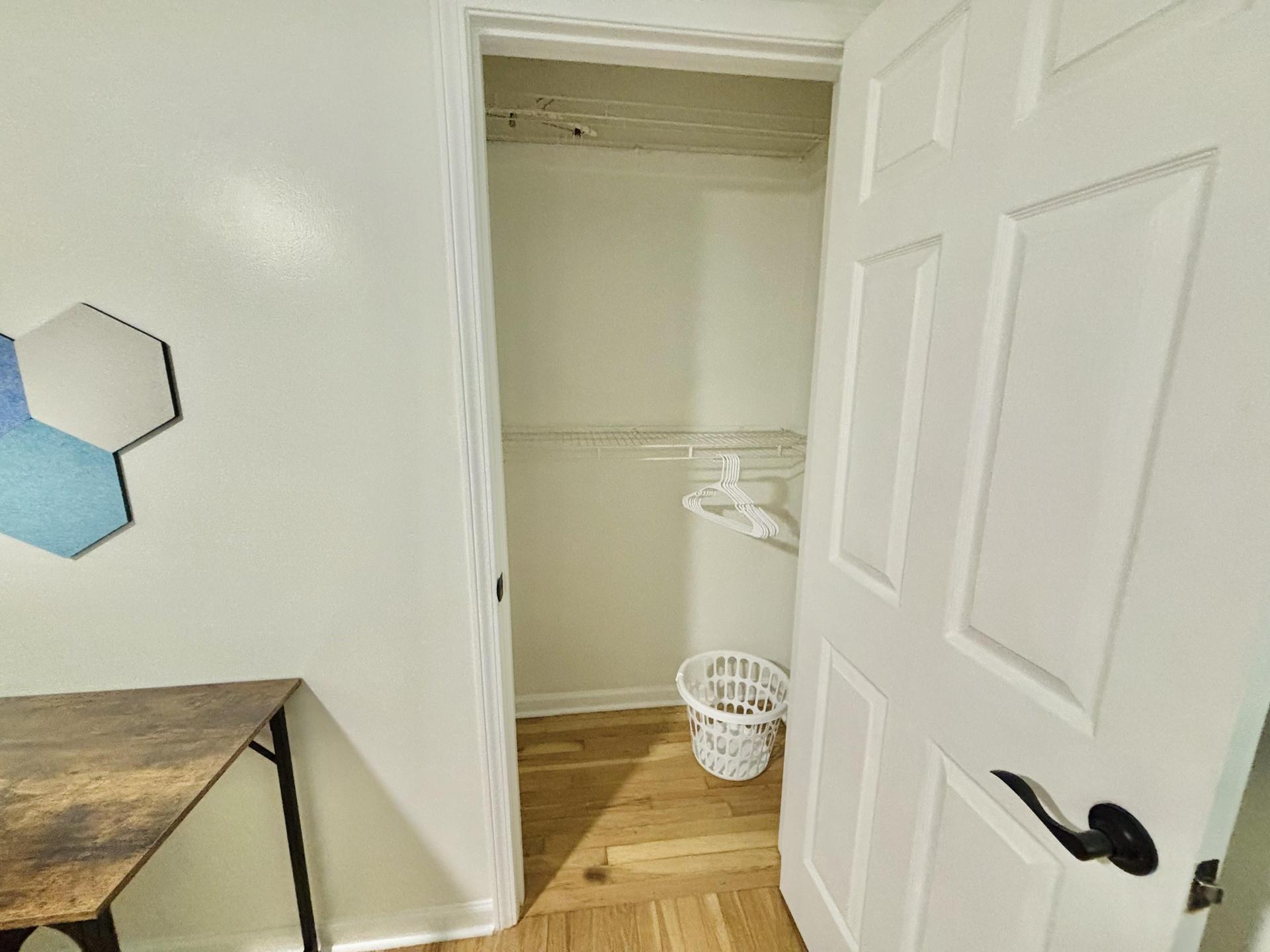 Very spacious closet with two racks, a few hangers and a laundry basket!