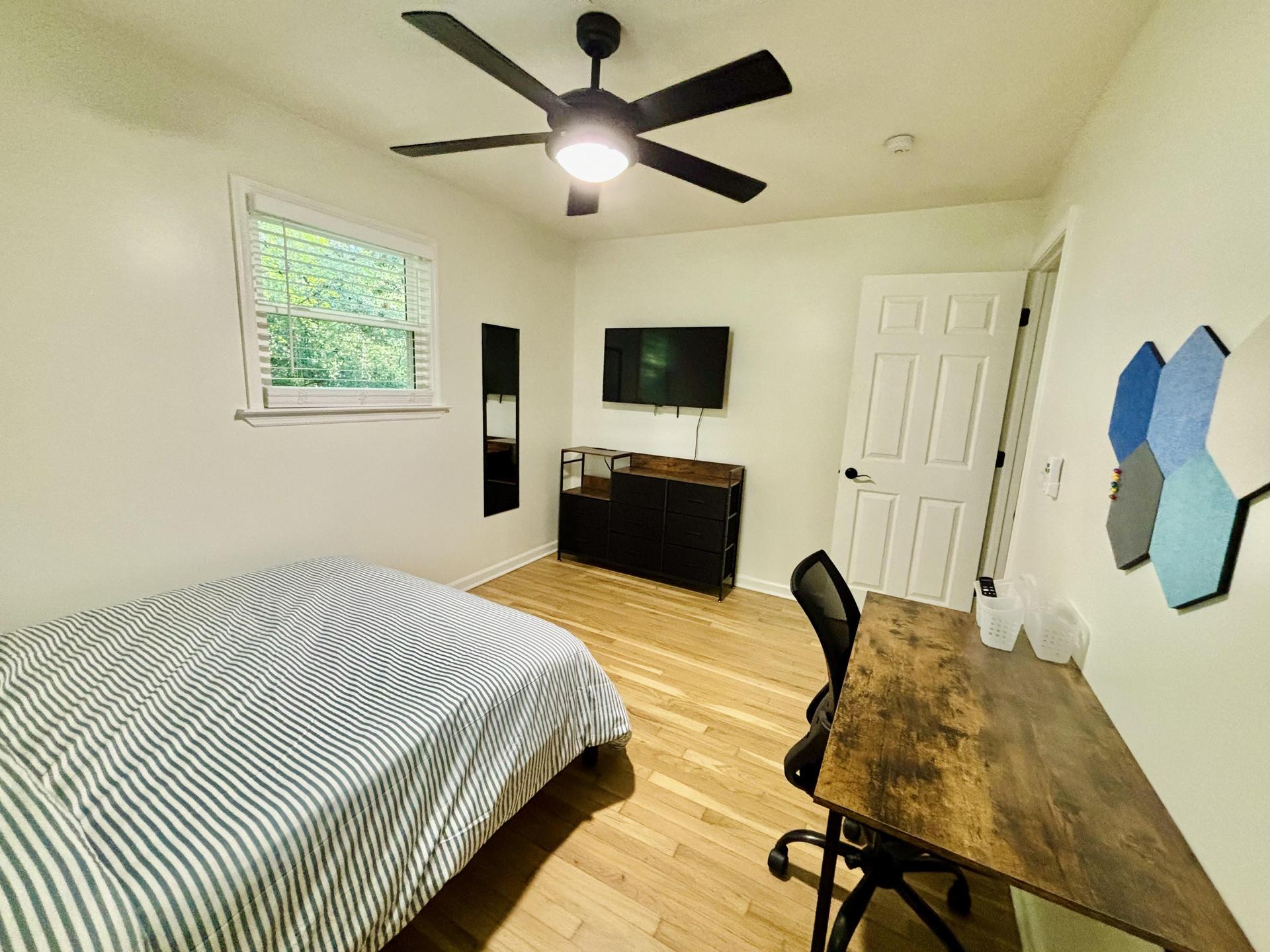 Spacious bedroom with full sized bed, mounted smart TV, desk & bulletin board, and full length mirror!