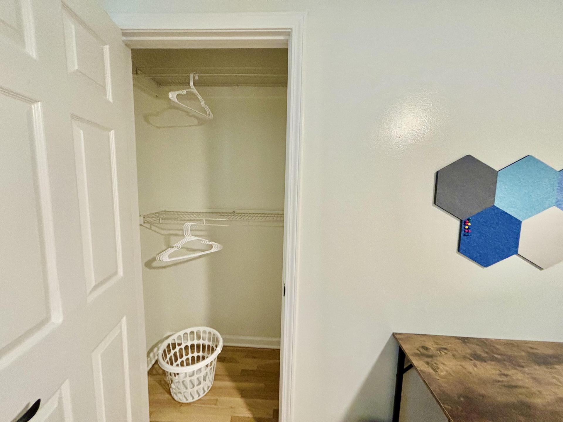 Very spacious closet with two racks, a few hangers and a laundry basket!