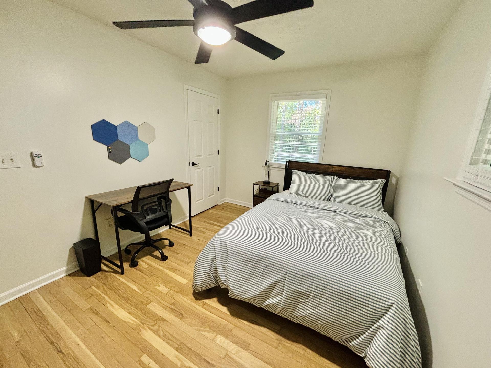 Spacious bedroom with full sized bed, mounted smart TV, desk & bulletin board, and full length mirror!