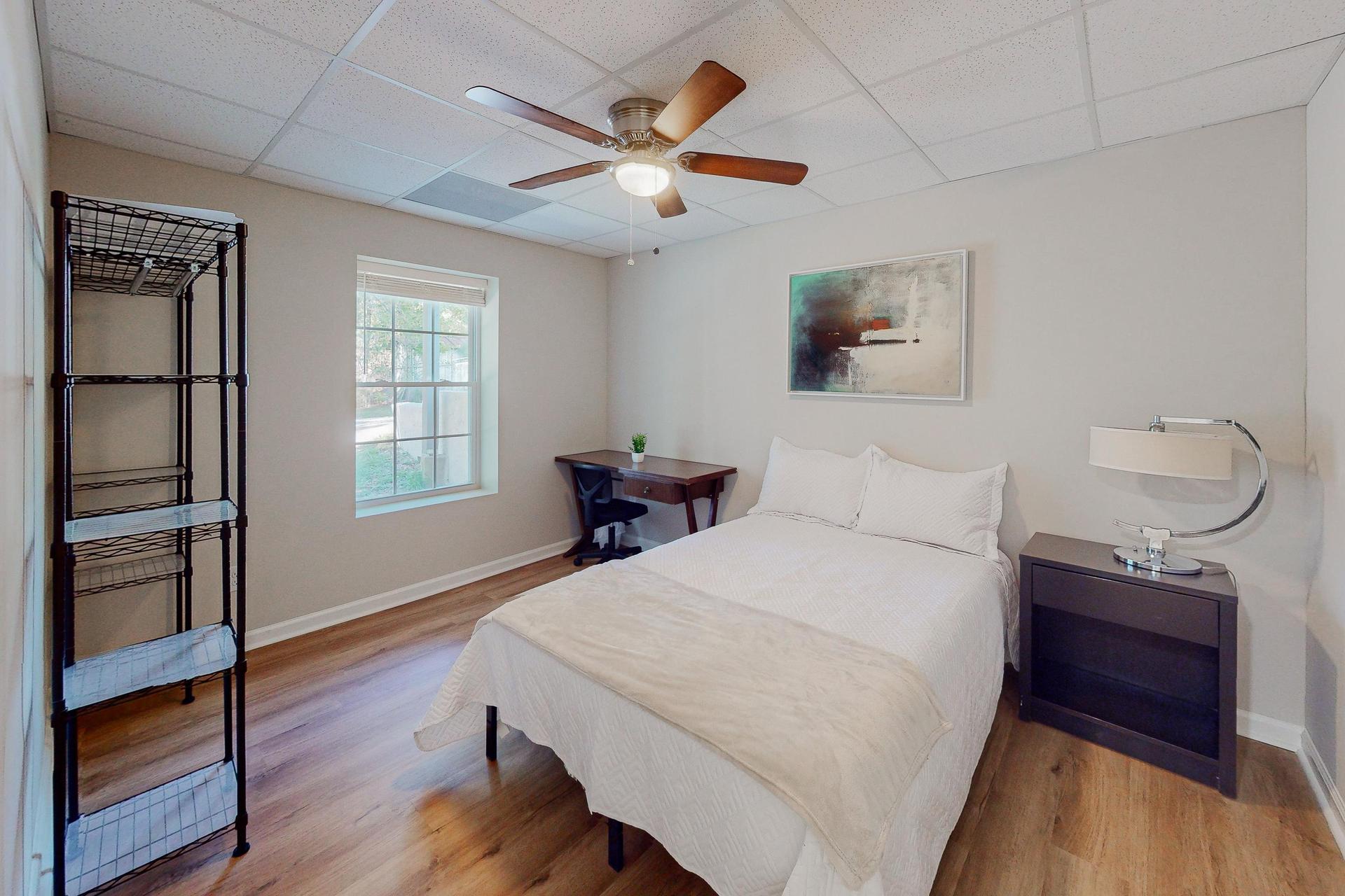 Bedroom complete with full sized bed, nightstand, desk, ceiling fan and clothes rack.