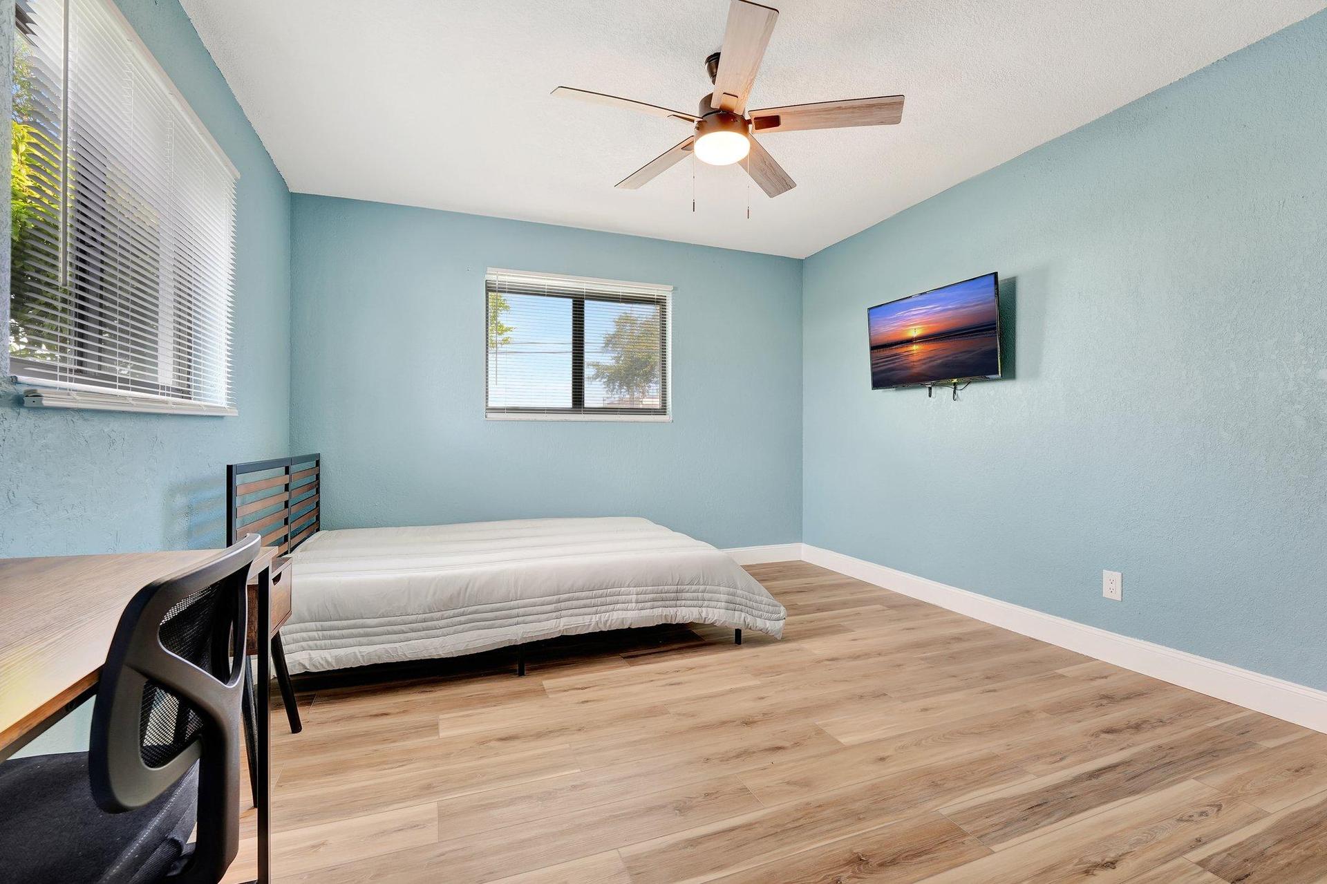 Large bedroom with tv and desk.