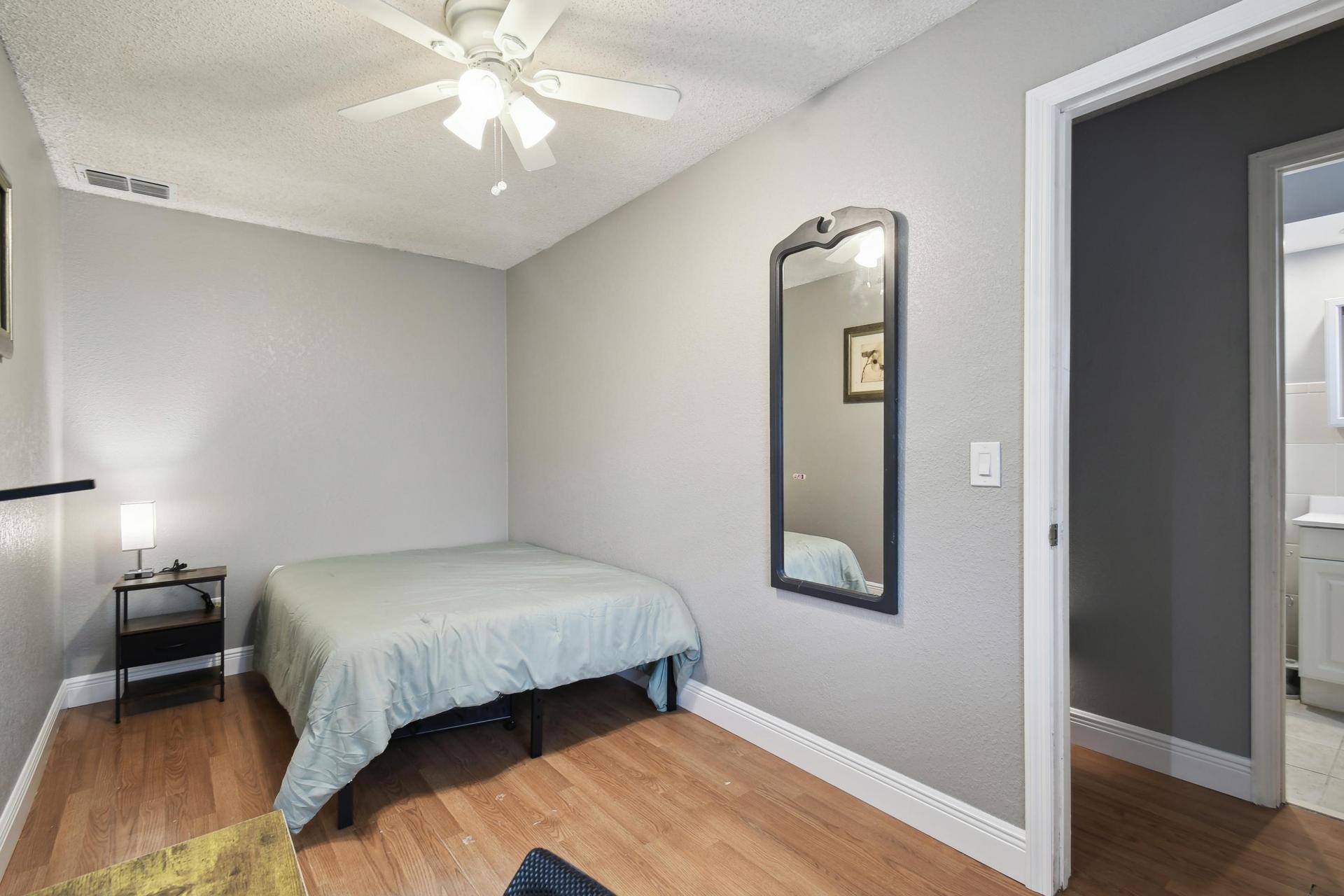 Full size cozy bed, with end table, light and storage container under the bed.