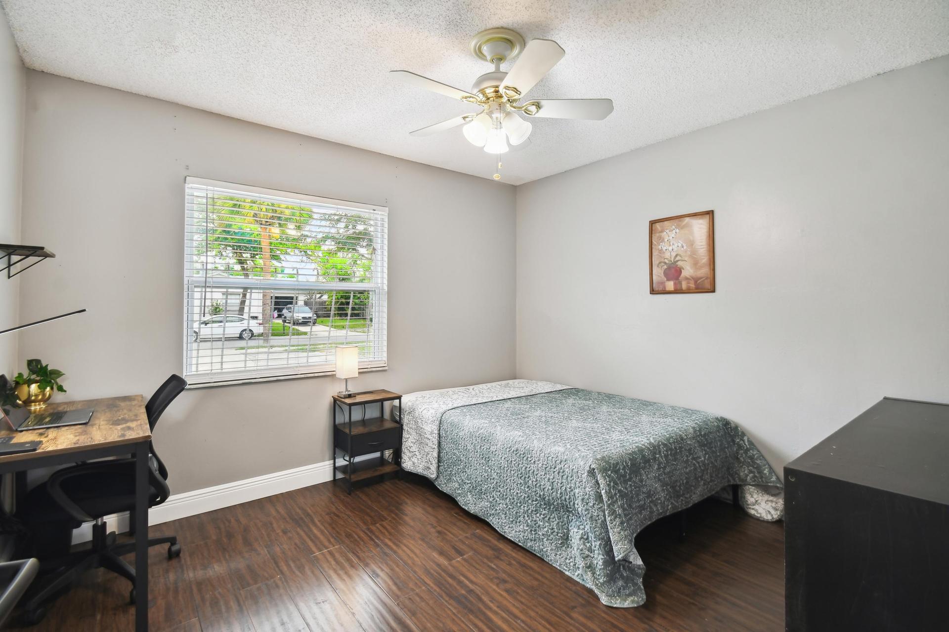 Full size cozy bed, with end table, light and storage container under the bed.