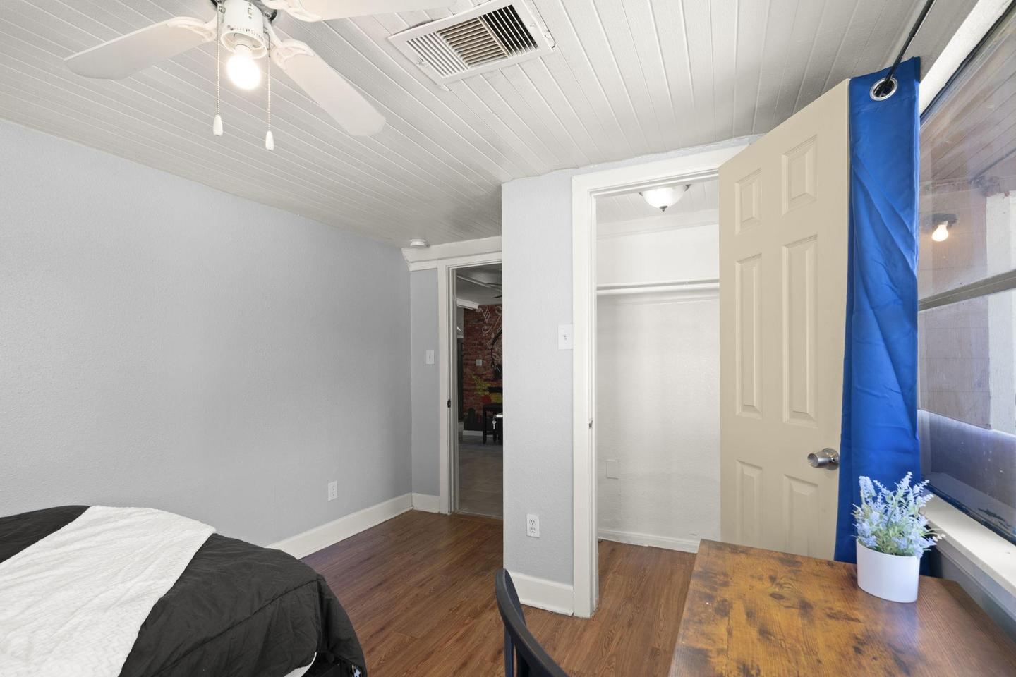 Rear home facing backyard with 2 windows and lots of light. Smart TV, ceiling fan, and desk.