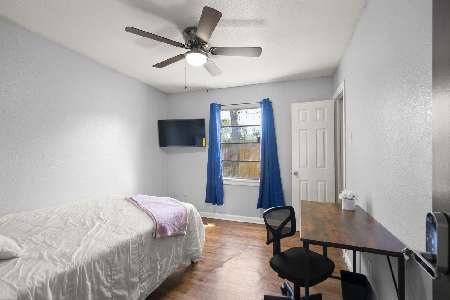 Hallway room near bathroom includes ceiling fan and smart TV